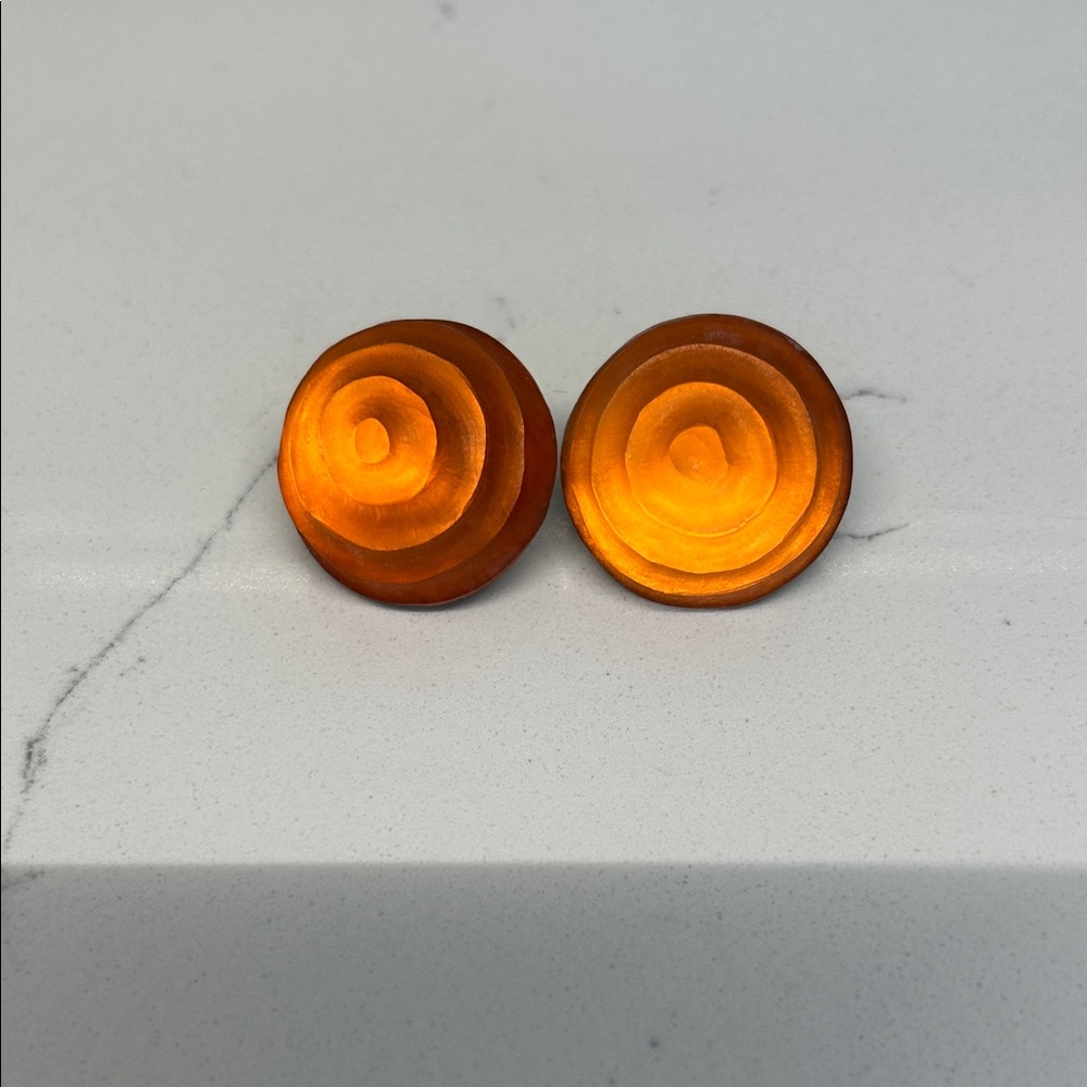 Alexis Bittar carved lucite swirl dome round clip earrings. Orange tone.